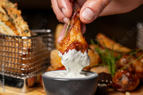 Photography Hand holding grilled chicken legs dipping in sauce and set of grilled black pepper chicken background