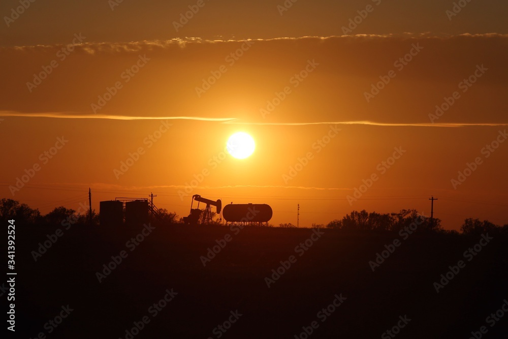 Fototapeta premium Sunsets on Oil industry’s pump jack and tanks
