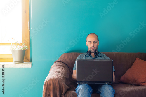 Man sitting on a sofa working from home with his laptop