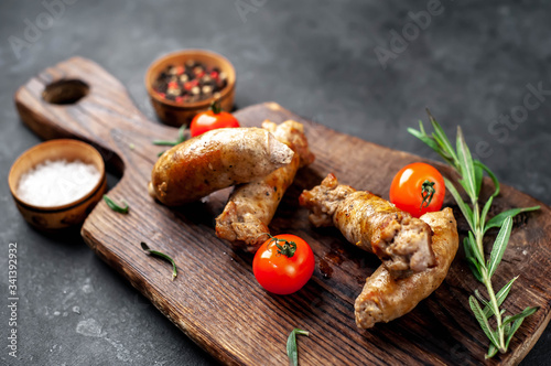 Grilled sausages with spices, tomatoes, rosemary on a stone background with copy space for your text