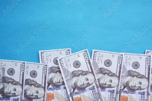 One hundred (100) dollar bills isolated on a blue background.