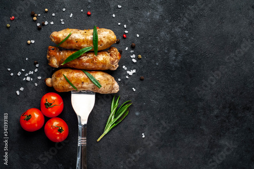 Grilled sausage on a fork with spices, tomatoes on a stone background with copy space for your text