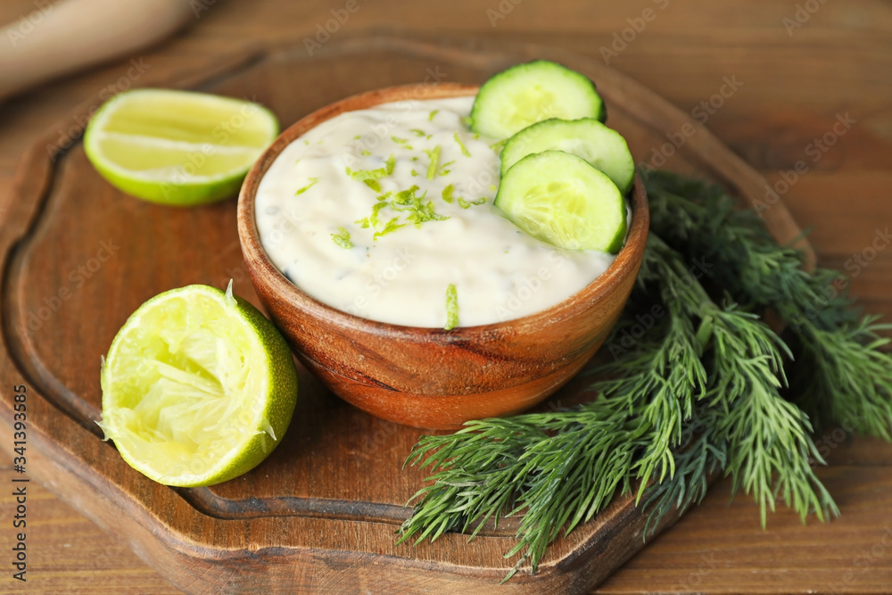 Delicious yogurt sauce with cucumber in bowl on wooden table Delicious yogurt sauce with cucumber in bowl on wooden table