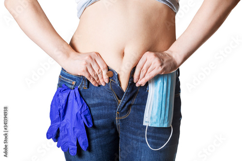 Young woman tries to button her jeans after quarantine. Concept of unhealthy lifestyle and overeating during self-isolation. Front view. Close shot
