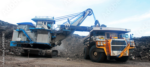 Heavy truck in a quarry transports coal loading excavator