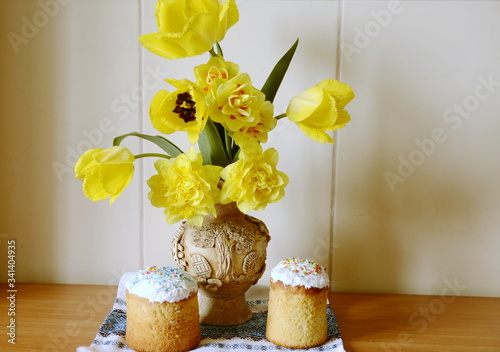 Religion and culture. Easter day. On the table are holiday cakes, a vase with beautiful yellow daffodils.