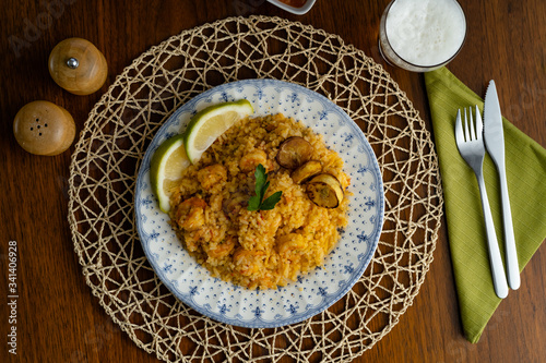 Rice with shrimp, traditional dish of Ecuadorian cuisine, served on wooden table, salt, pepper and glass of beer