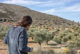 Photographs taken in the field in Guadalajara, Spain. Woman from behind looking at the landscape from the top of a hillside and smelling flowers