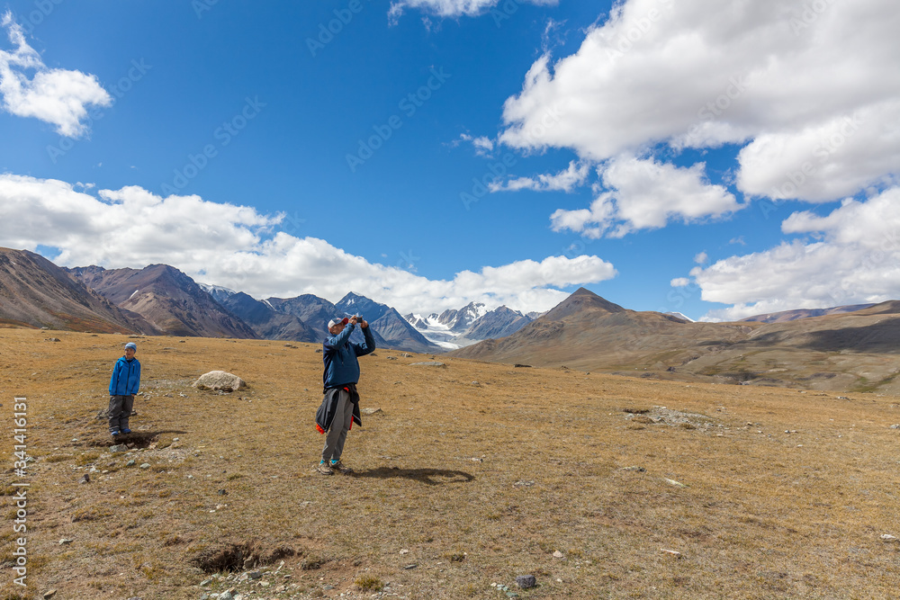 Hiker young man and boy in the Altai mountains of Mongolia. Enjoy the scenery and take pictures of it.