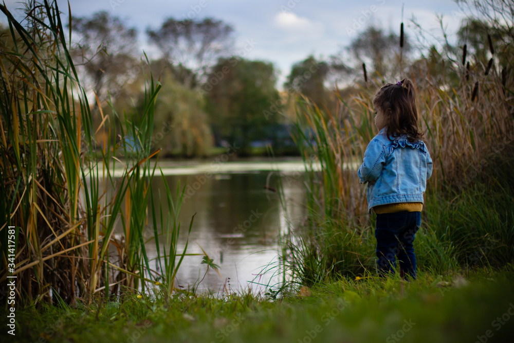 a child playing in the park alone near a pond or lake a child playing in the park alone near a pond or lake