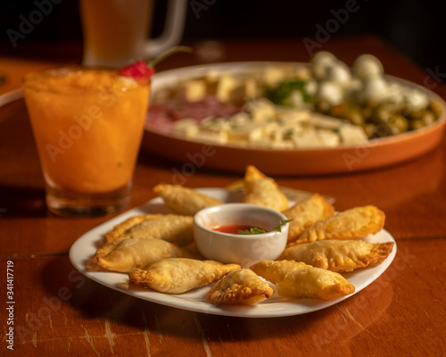 Brazilian snacks on bar table. Fried pastry and cold appetizers. Mug of beer chop and glass in caipirinha. 