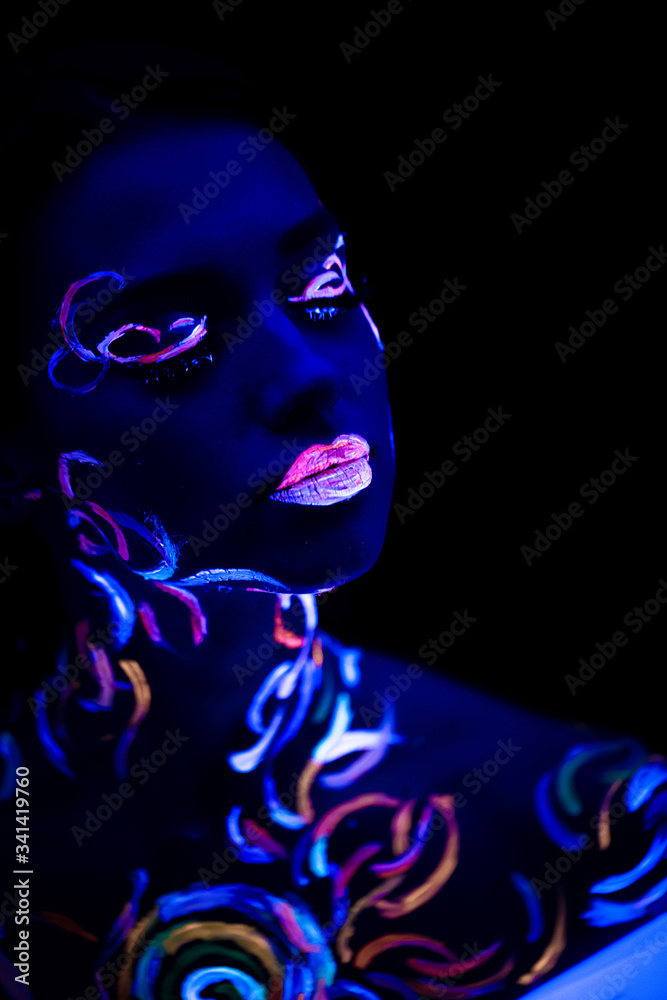 fantastic unusual shot of young caucasian woman with fluorescent make-up glowing in ultra-violet light. body art on attractive woman, unusual colorful design fantastic unusual shot of young caucasian woman with fluorescent make-up glowing in ultra-violet light. body art on attractive woman, unusual colorful design
