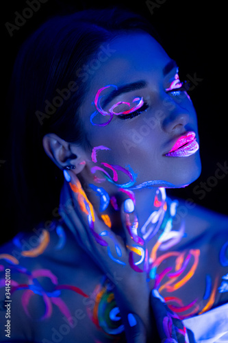 sensual caucasian girl with fluorescent body art posing at camera. fantasy, creative art, body art, fluorescent, luminescence, design concept