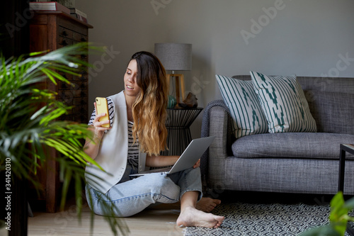 Mujer joven trabajando en casa con su ordenador y su teléfono movil