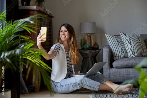Mujer joven trabajando en casa con su ordenador y su teléfono movil