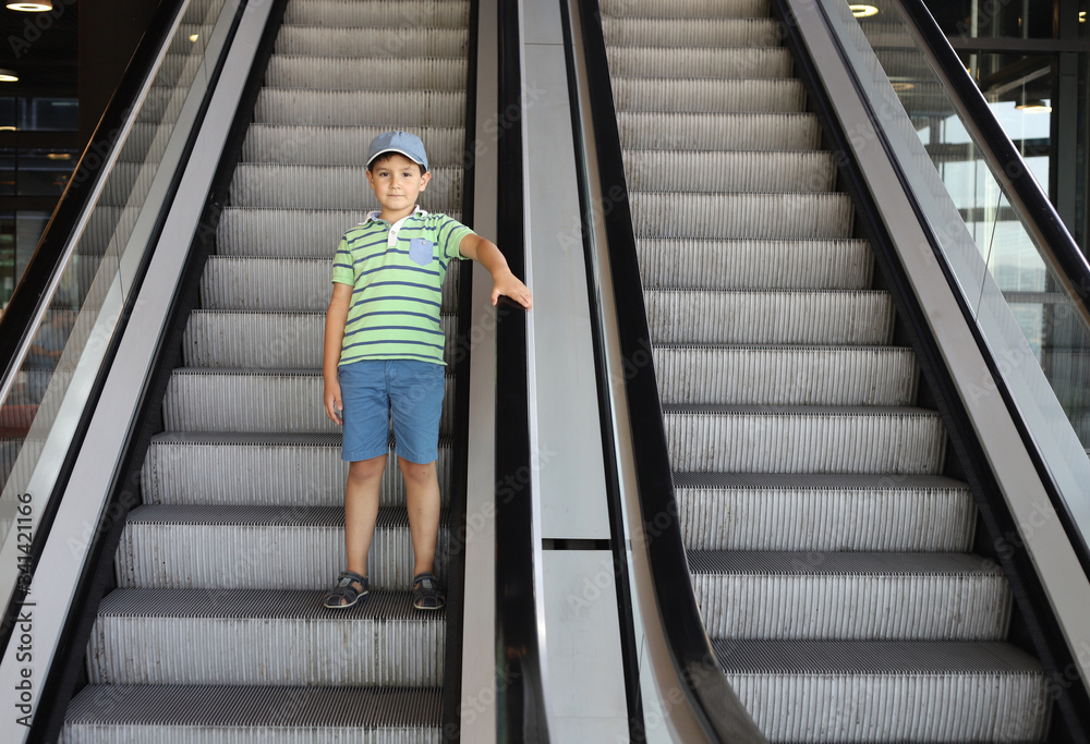 niño bajando escaleras mecánicas agarrado al pasamanos