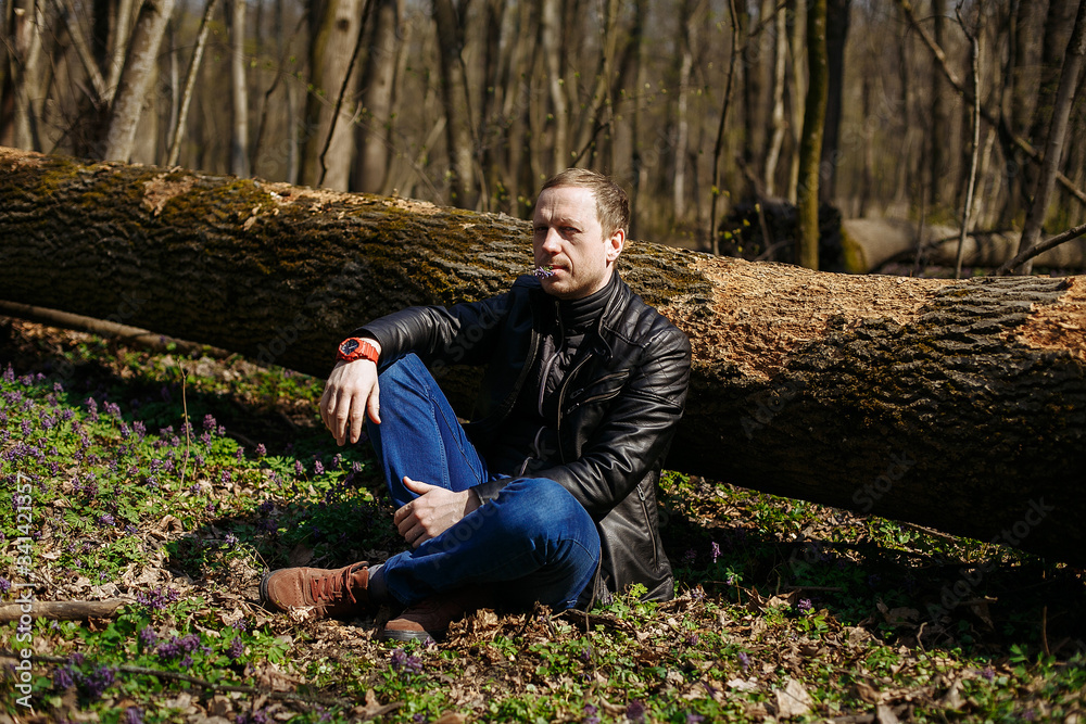 a man sits under a fallen tree in the forest a man sits under a fallen tree in the forest
