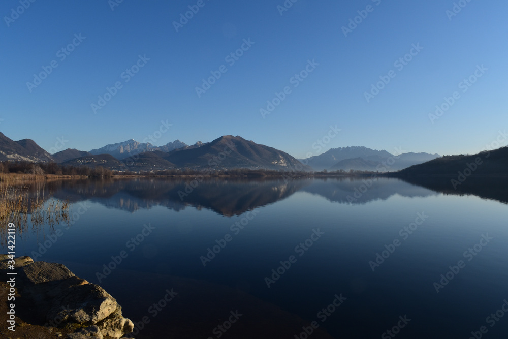Alserio lake Como Italy - mountain reflected on the water - blue sky - Lago di Alserio