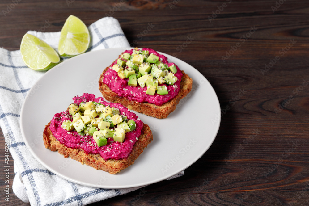Variation of healthy rye toasts with avocado and beetroot on a plate. Delicious snacks, avocado sandwiches. Food composition, tasty italian meal. Close up, top view Variation of healthy rye toasts with avocado and beetroot on a plate. Delicious snacks, avocado sandwiches. Food composition, tasty italian meal. Close up, top view