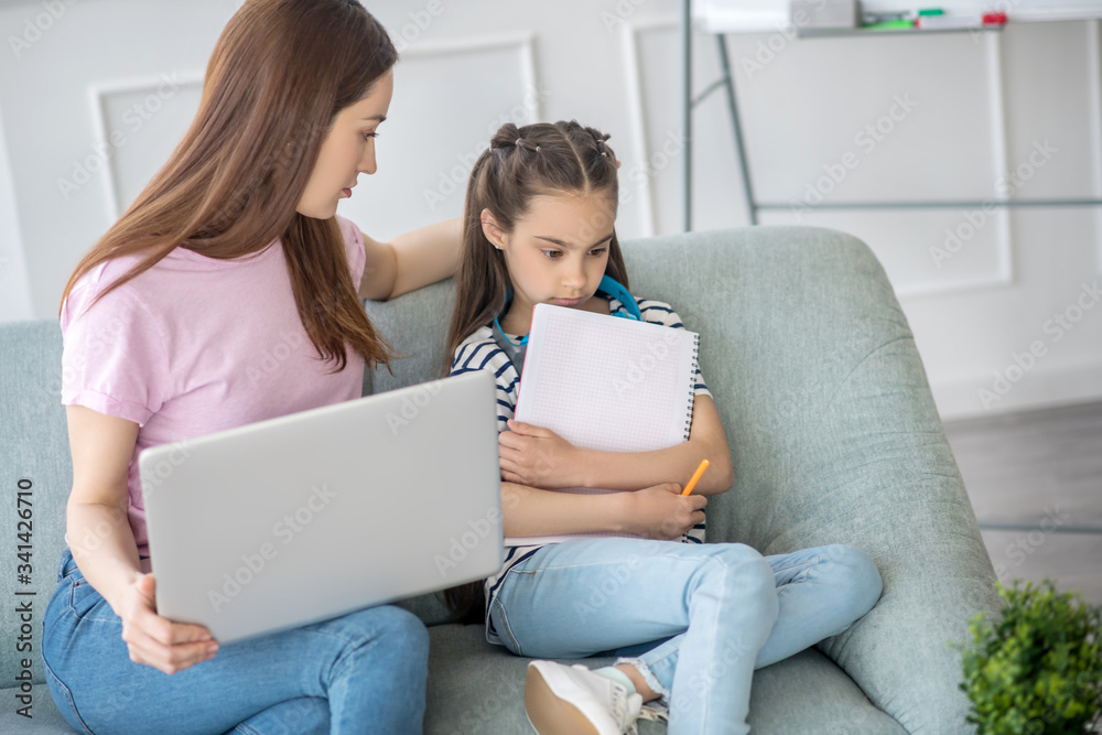 Bored daughter and caring mom with a laptop. Bored daughter and caring mom with a laptop.