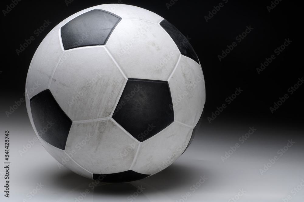A close up of a classic soccer ball over a black background.