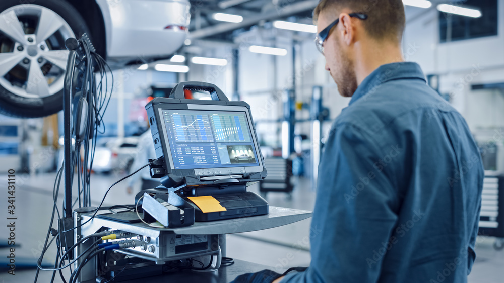 Fototapeta premium Car Service Manager or Mechanic is Running an Interactive Diagnostics Software on an Advanced Computer. Specialist Inspecting the Vehicle in Order to Find Broken Components and Errors in Data Logs.