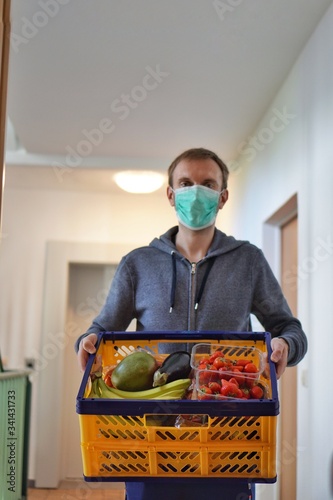 Lebensmittellieferung von Obst und Gemüse in Corona Krise vor die Haustür mit Schutzmaske wegen Virus Gefahr