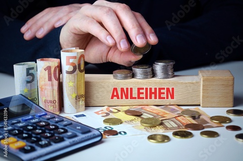 Anleihen. Mann stapelt Geld (Euro). Begriff Anleihen auf Baustein. Münzen, Scheine & Taschenrechner. Konzept für Business, Finanzen, Wirtschaft photo