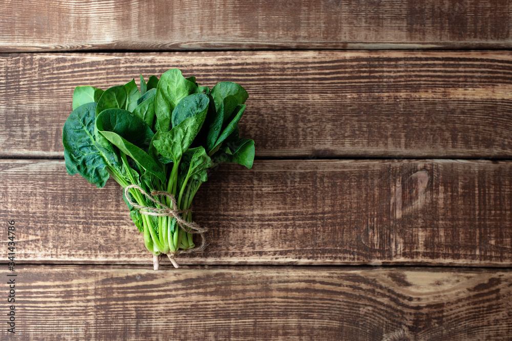 Fototapeta premium Clean food concept. Leaves of ripe juicy freshly picked organic spinach greens on a wooden background. Healthy detox spring-summer diet. Vegan Raw Food. Copy space.