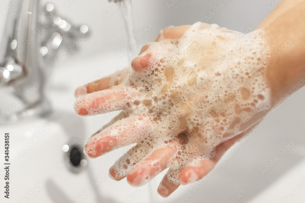 Fototapeta premium Rubbing fingers, Washing hands with antibacterial soap in proper technique on background of flowing water in white bathroom. Prevention coronavirus. Cleaning and disinfecting