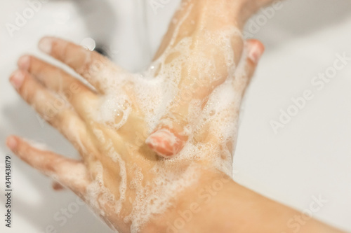 Rubbing big thumb, Washing hands with antibacterial soap in proper technique on background of flowing water in white bathroom. Prevention coronavirus. Cleaning and disinfecting