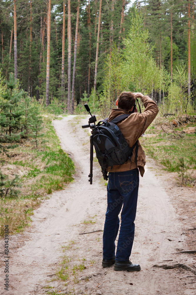 Photographer on a forest road. Photographing a spring landscape