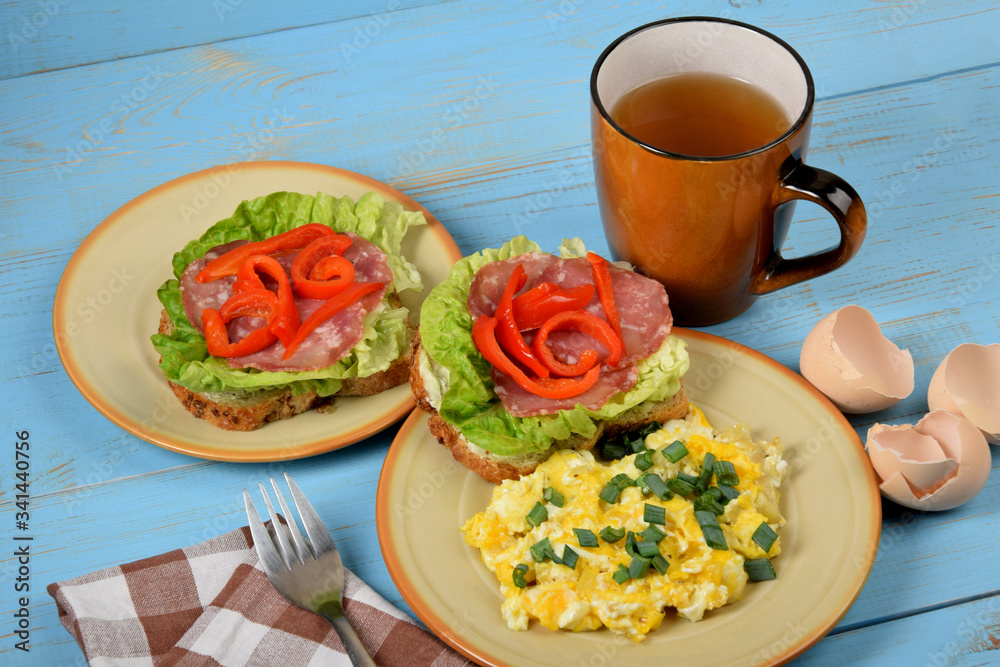 scrambled eggs with chives, a colorful sandwich and tea on an old blue table scrambled eggs with chives, a colorful sandwich and tea on an old blue table