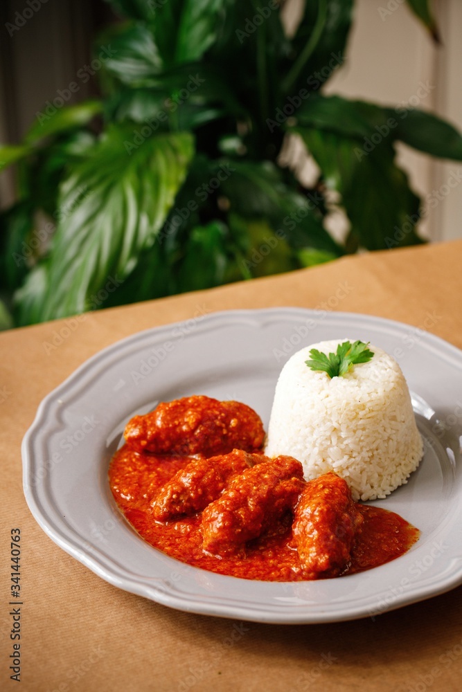 Chicken fillet with red sauce and rice on the side presentable main course plating. Authentic Mediterranean cuisine photography in wooden background. Chicken fillet with red sauce and rice on the side presentable main course plating. Authentic Mediterranean cuisine photography in wooden background.