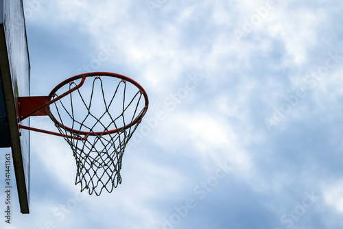 Dark silhouette of street basketball hoop an a cloudy day. Close up of hoop net. Urban youth game © CrispyMedia