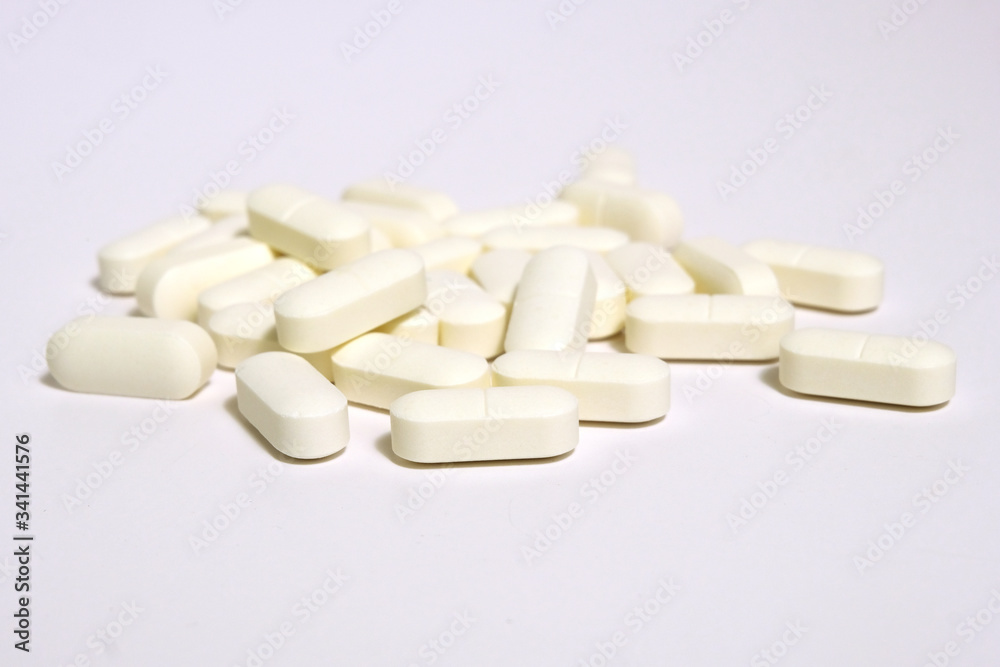 Selective focus on white pills spread on white background with shadow. Global healthcare concept. Antibiotics drug resistance. Antimicrobial pills macro. Pharmaceutical industry. Selective focus on white pills spread on white background with shadow. Global healthcare concept. Antibiotics drug resistance. Antimicrobial pills macro. Pharmaceutical industry.