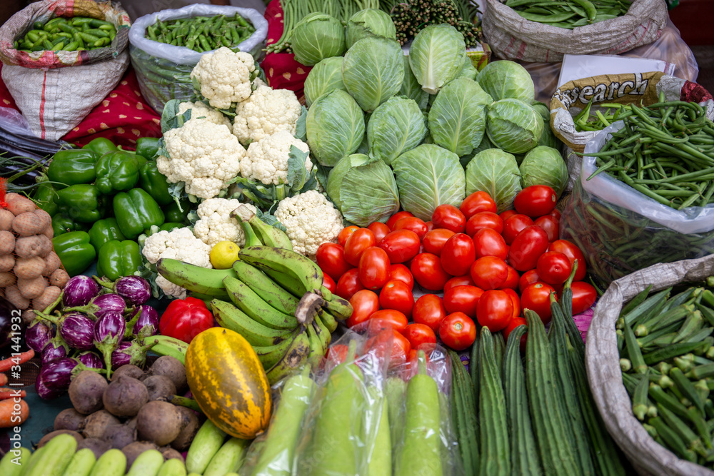 Tomatoes, cucumbers, aubergines, eggplants, cauliflowers and other fresh vegetables on sale in the middle of the street, in an indian food market in Mumbai.