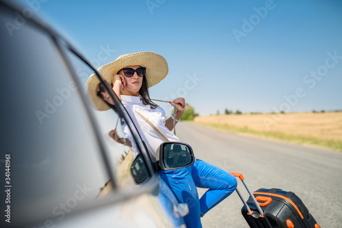 young happy beautiful model near her car on summer trip.