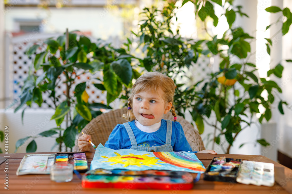 little toddler girl painting rainbow and sun with water colors during pandemic coronavirus quarantine disease. Children painting rainbows around the world with the words Let's all be well. Happy child little toddler girl painting rainbow and sun with water colors during pandemic coronavirus quarantine disease. Children painting rainbows around the world with the words Let's all be well. Happy child