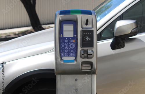 Canvas Print Top of a new digital coin and card operated parking meter with a parked car in background