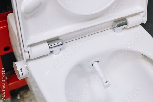 Toilet bowl with manual control bidet. Water sprays from the toilet bowl. A cleansing jet of water designed to cleanse the anus of the user of this bidet-style toilet.
