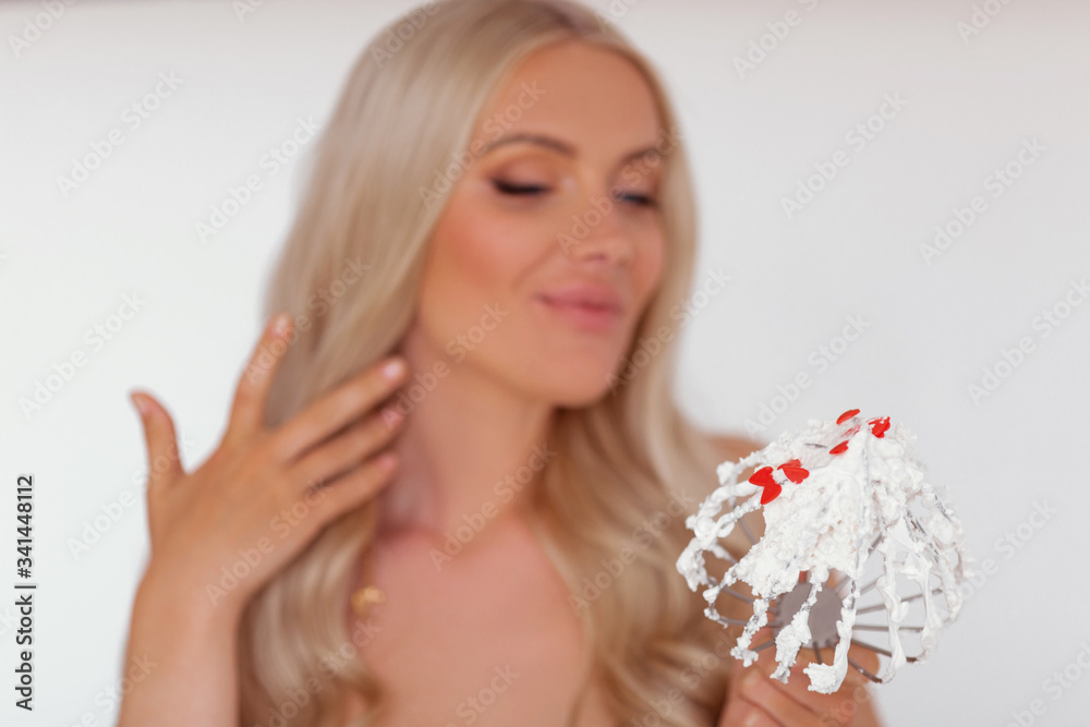 Happy young woman with candies on her tongue in shape of hearts is licking whisk with sweet cream. Happy young woman with candies on her tongue in shape of hearts is licking whisk with sweet cream.