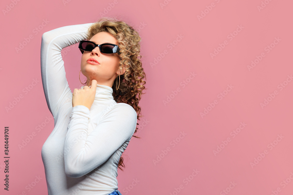 beautiful young woman   with curl hair and black modern glasses posing  on pink   background   - Image