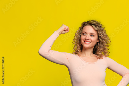 beautiful young woman with curl hair posing on yellow background - Image
