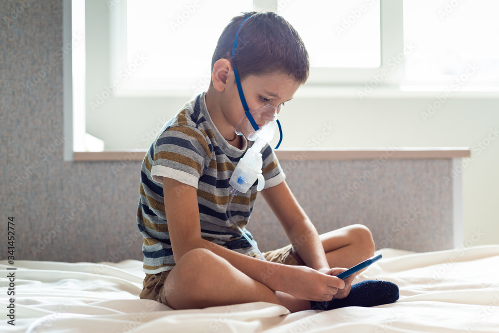 Stay at home quarantine coronavirus pandemic prevention.Stay at home quarantine coronavirus pandemic prevention. A child in an oxygen mask with a nibulizer plays on a mobile phone during quarantine. P Stay at home quarantine coronavirus pandemic prevention.Stay at home quarantine coronavirus pandemic prevention. A child in an oxygen mask with a nibulizer plays on a mobile phone during quarantine. P