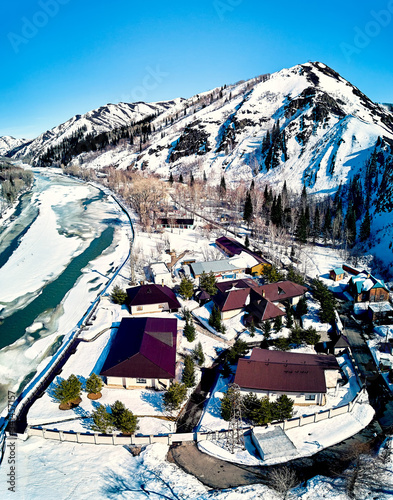Panoramic aerial view: beautiful spring landscape: the Ulba river in Kazakhstan wakes up from winter sleep - ice drift - snow and ice are melting in the mountains, the bright sun is shining photo