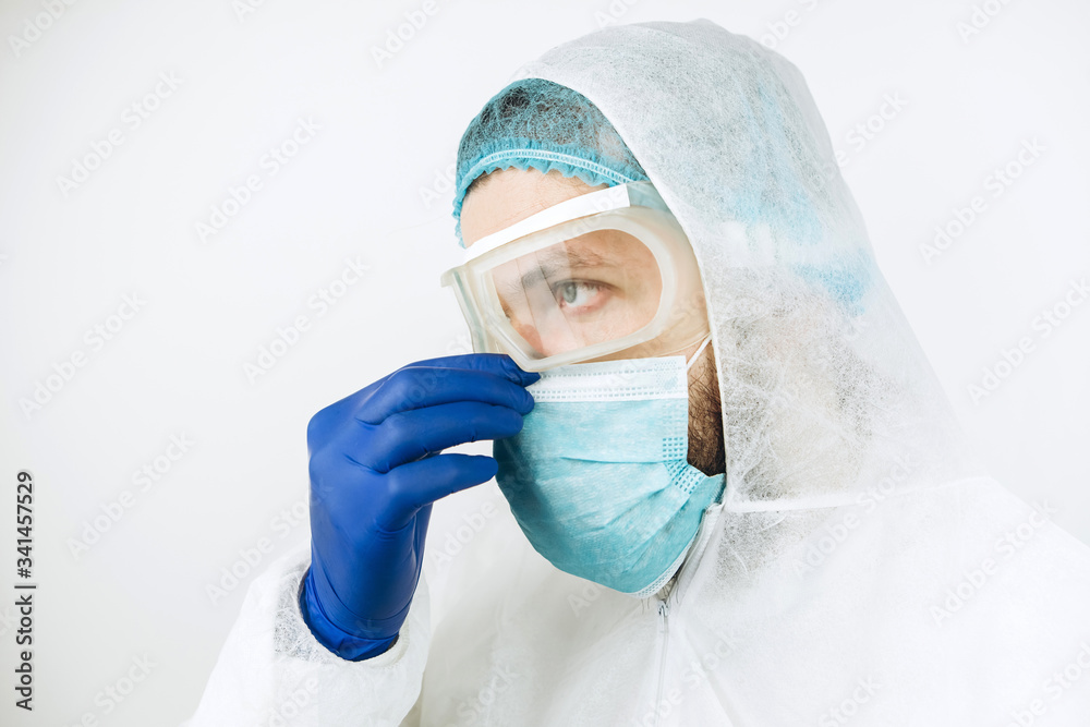 Naklejka premium close-up portrait of tired doctor after shift in the hospital. The doctor in protective clothing - glasses, mask, gloves on white background. The doctor treating patients with coronavirus. Covid-2019