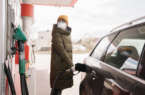 Woman wearing face mask fulfilling tank in the petrol station