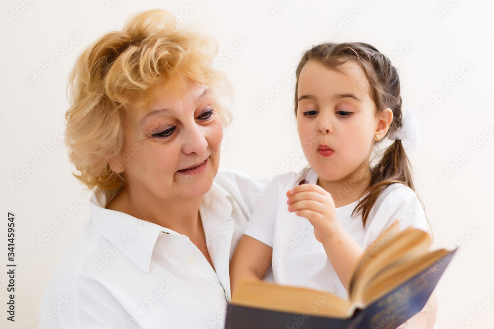 little girl with grandma reading interestng book little girl with grandma reading interestng book