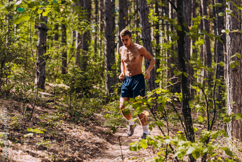 Full body portrait of a fit man running outdoors through mountain